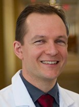 Dr. Carsten Skarke smiling headshot in white laboratory coat